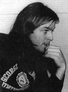 black and white photograph of a man with long hair wearing a fire department shirt looking to his left