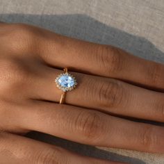 a woman's hand with a ring on it and a blue stone in the middle