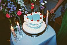 there is a cake on the table with candles in front of it and some flowers