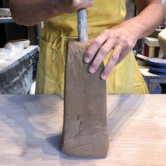 a man is working with clay on a piece of wood that has been shaped into a hammer