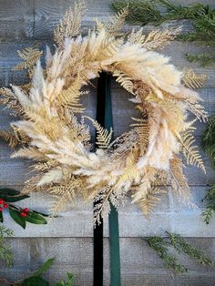 a christmas wreath on top of a wooden table next to evergreen leaves and holly berries