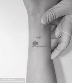 a small cactus tattoo on the left inner forearm and wrist is shown in this black - and - white photo