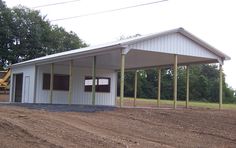 a small white building sitting on top of a dirt field next to a green tractor