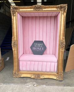 a gold frame with a pink velvet bench in it and a sign that says honey