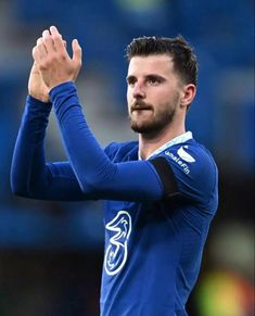 a soccer player is applauding the crowd with his hands in the air as he looks on