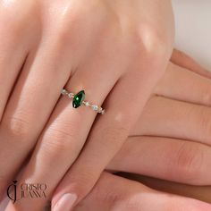 a woman's hand with a ring on her finger and an emerald stone in the middle