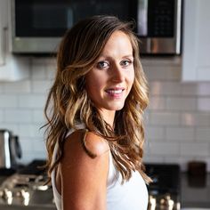 a beautiful young woman standing in front of a stove top oven