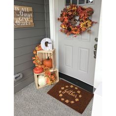 the front door is decorated for fall with pumpkins, leaves and an autumn wreath