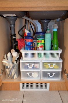 under the kitchen sink is organized with plastic bins