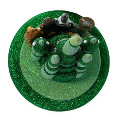 there is a green cake decorated with animals and other things on the top of it