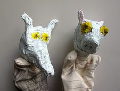 two paper mache animals sitting next to each other on top of a white wall