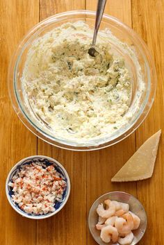 shrimp and cheese dip in a glass bowl next to two small bowls with crackers on the side