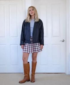 a woman standing in front of a white door wearing brown boots and a blue jacket