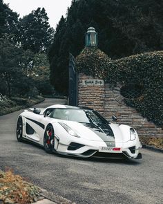 a white sports car parked in front of a stone wall and entrance to a building