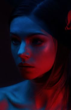 a woman with red and blue light on her face, looking down at the camera