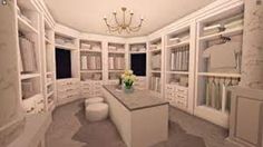 a large walk in closet filled with lots of white cabinets and drawers next to a chandelier