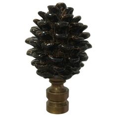 a black pine cone on a brass base