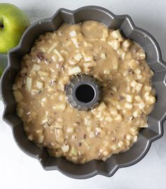 an apple pie with caramel topping in a bundt pan next to an apple