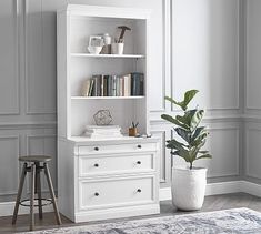 a white bookcase with two drawers and a potted plant in the corner next to it