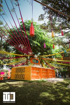 an orange crate under a tree with red lanterns hanging from it's branches and colorful streamers