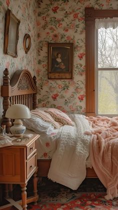 a bedroom with floral wallpaper and pink bedspread in front of a window