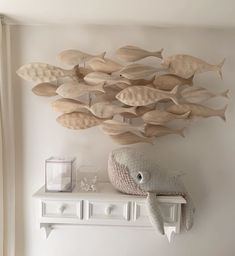 a white shelf topped with a stuffed animal next to a wall mounted fish sculpture on it's side