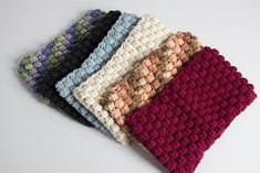 four crocheted dishcloths sitting on top of each other in different colors