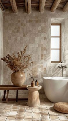 a large white bath tub sitting next to a wooden bench in a room with stone walls