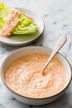 a bowl of soup next to a plate with lettuce on it