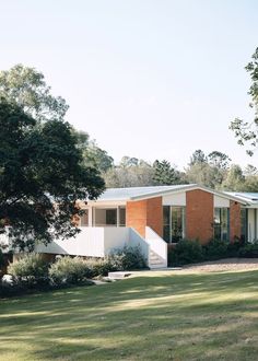 a house in the middle of a field with trees and grass on both sides of it