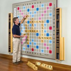 a man standing in front of a giant scrabble board