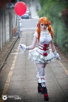 a woman dressed in white and red is walking down the street with a balloon behind her