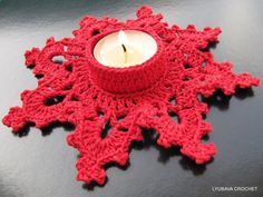 a red crocheted candle holder with a lit candle