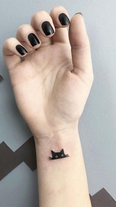 a small black cat tattoo on the left wrist and right hand with it's paw in the air