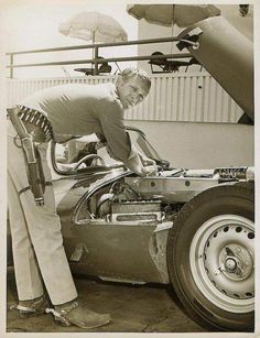 an old photo of a man working on a car