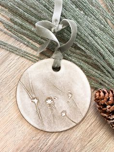 a ceramic ornament with flowers on it next to a pine cone