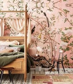 a bedroom decorated in pink and green with birds on the tree wallpaper, along with two chairs