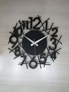 a black clock with numbers and arrows on the face that reads twelve o'clock