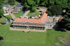 an aerial view of a large brick building in the middle of a lush green field