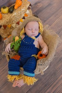 a newborn baby wearing a blue crochet outfit and hat laying in a basket