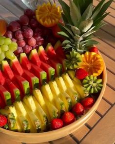 a bowl filled with lots of different types of fruit on top of a wooden table