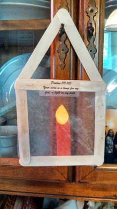 a red candle is in a clear box on a shelf next to other plates and pans