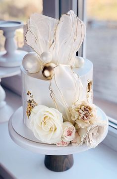 a wedding cake with white flowers and gold decorations