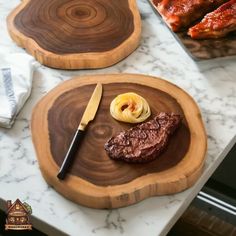 two wooden trays with food on them sitting on a marble counter top next to a cookbook