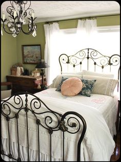 a bedroom with a white bed, chandelier and window in it's corner