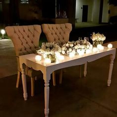 two chairs sitting next to each other with flowers and candles on top of the table