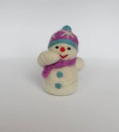 a small white snowman with a purple hat and scarf on it's head