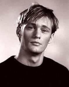 black and white photograph of a young man with his hair pulled back in a bun