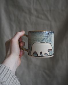 a hand holding a coffee cup with an image of a bear on it