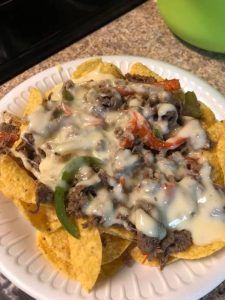 a white plate topped with nachos covered in cheese and sauce on top of a counter